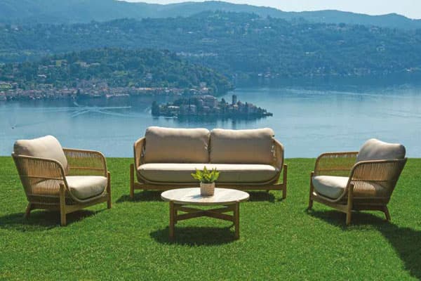 Complementi arredo giardino Didò Floricoltura targati Greenwood, divani e poltroncine con struttura in acacia e cuscini sfoderabili color sabbia con tavolino situati su un prato in una villa in che affaccia sul lago